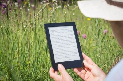 Person reading eBook while sitting on grass.